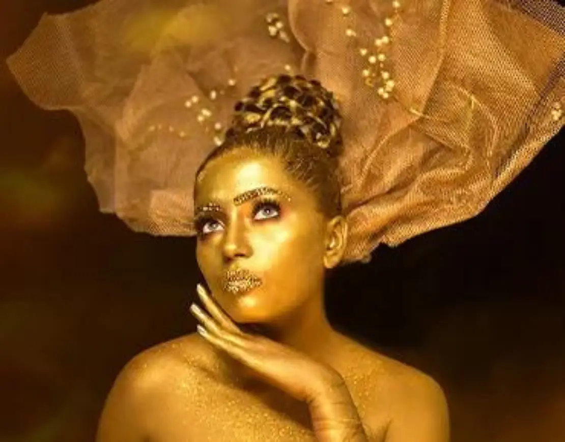 Model wearing golden dress and golden makeup