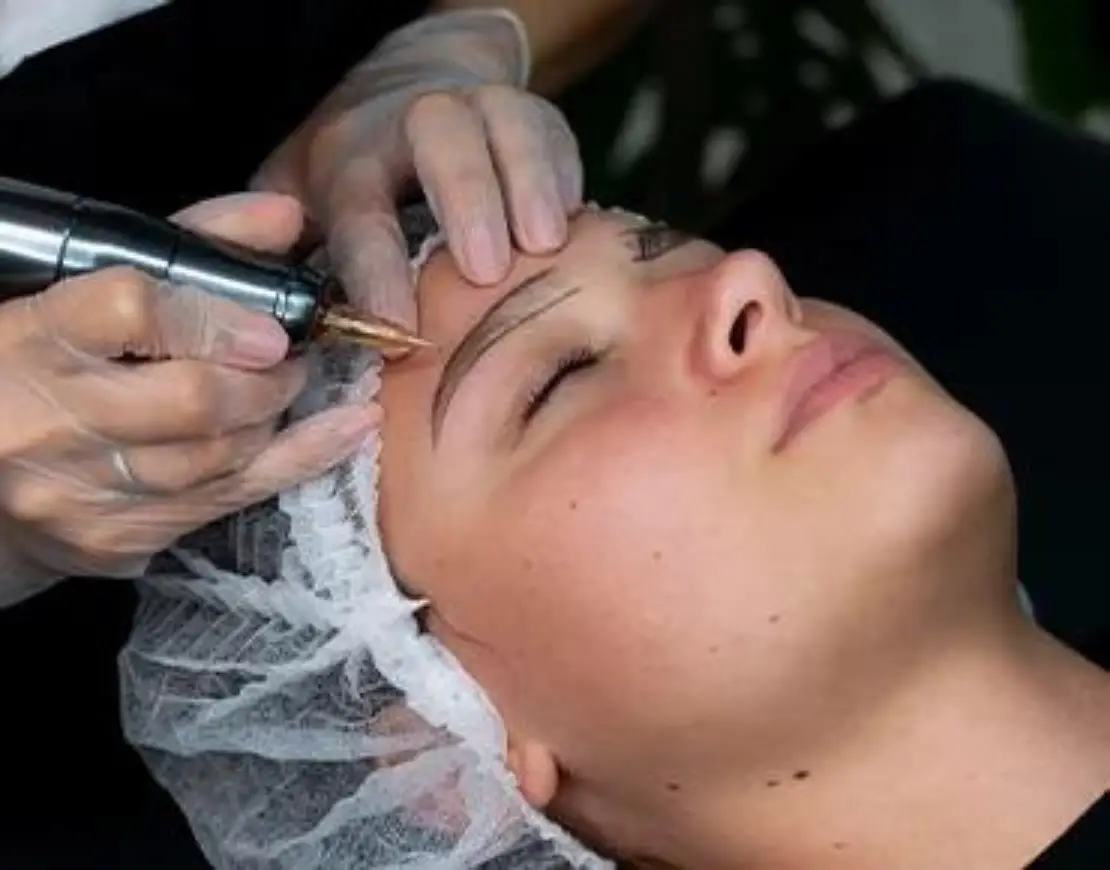 A woman undergoing an eyebrow grooming procedure with an electric device, highlighting the modern techniques in beauty care.