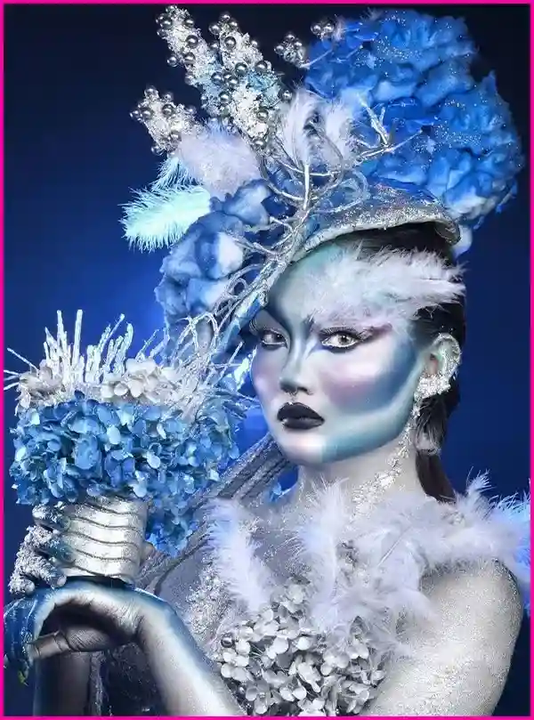  A woman adorned with blue and white makeup, complemented by elegant feathers, showcasing a striking and artistic appearance.