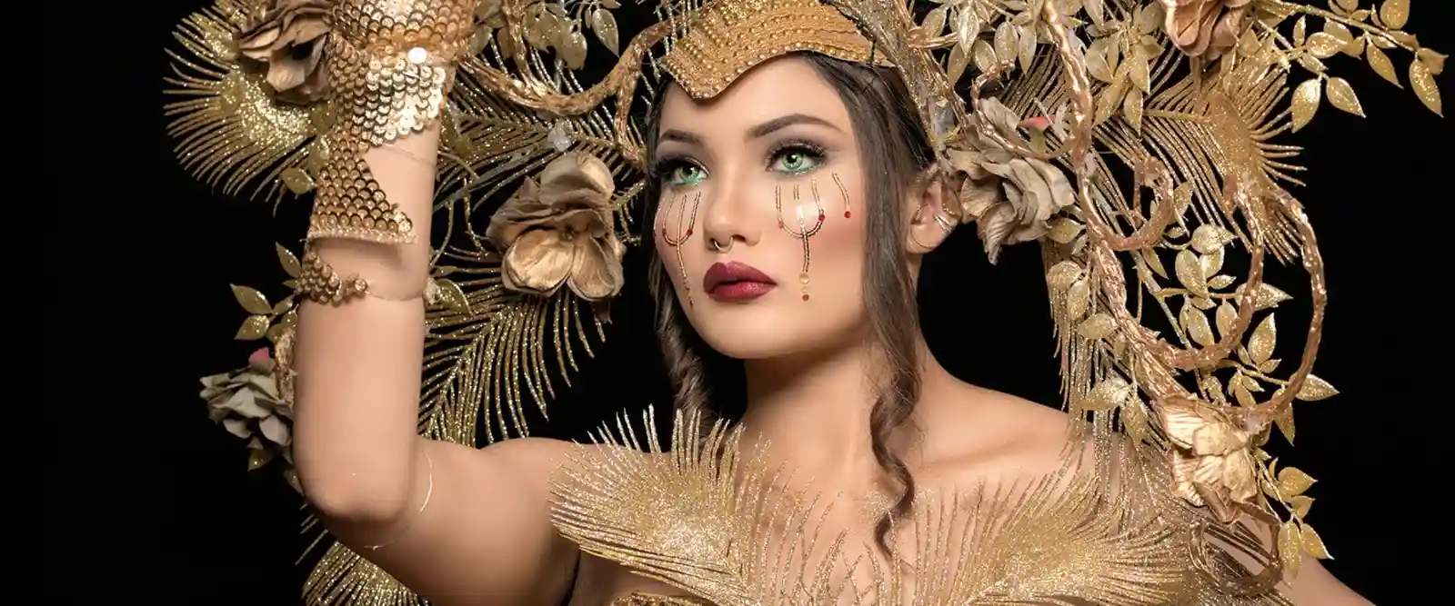 IWoman wearing heavy makeup in a golden attire and head gear. 