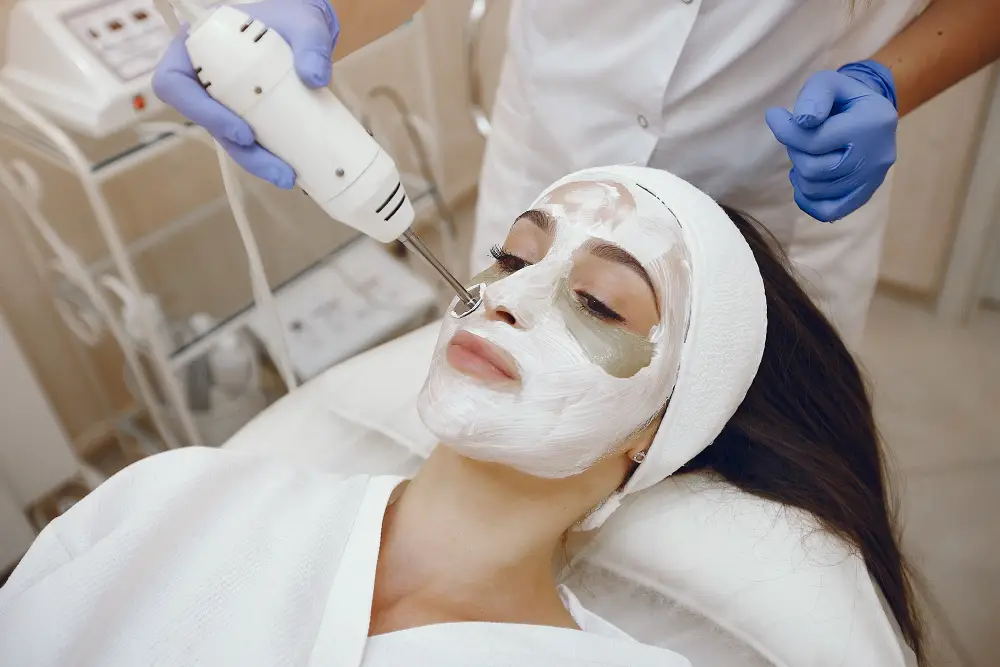 Woman undergoing facial treatment with white mask on her face.